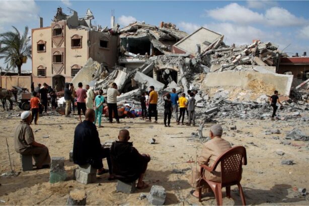 Gazanen staan bij de puinhopen van een aan flarden gebombardeerd pand
