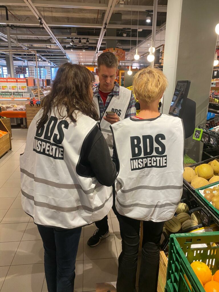 BDS Inspectie Amsterdam door twee mensen met witte hesjes, op de rug gezien