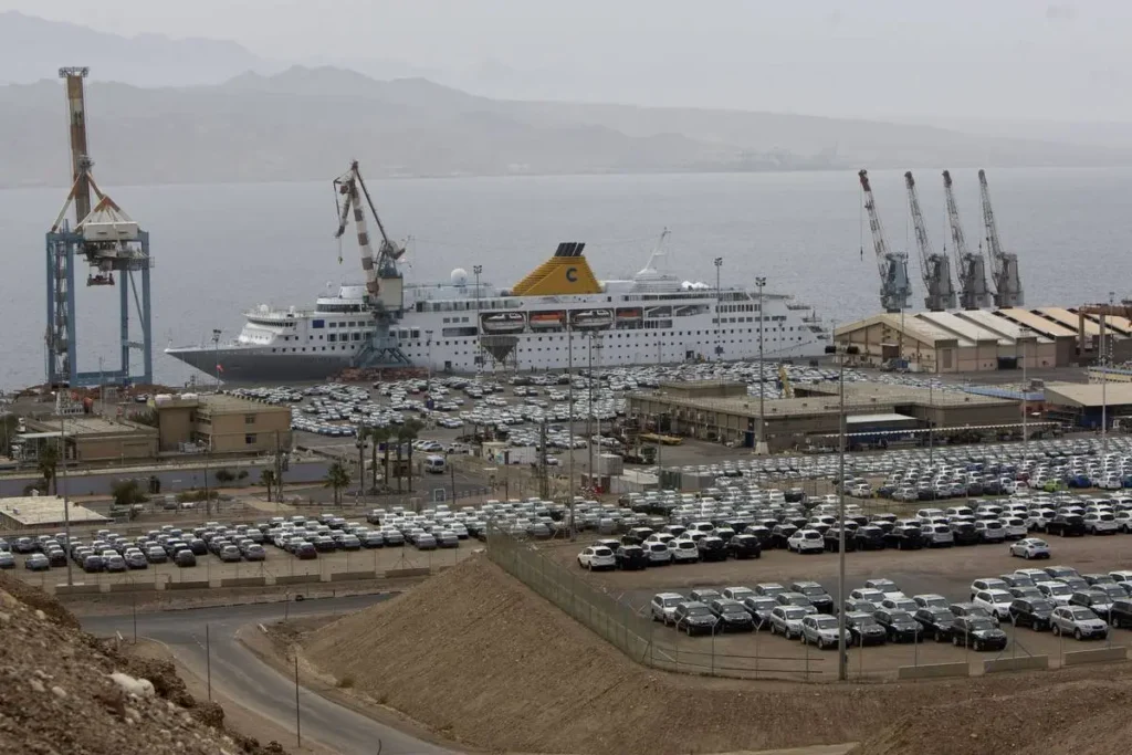 Schip in de haven van Eilat aan de Rode Zee, met geparkeerde auto's op de voorgrond