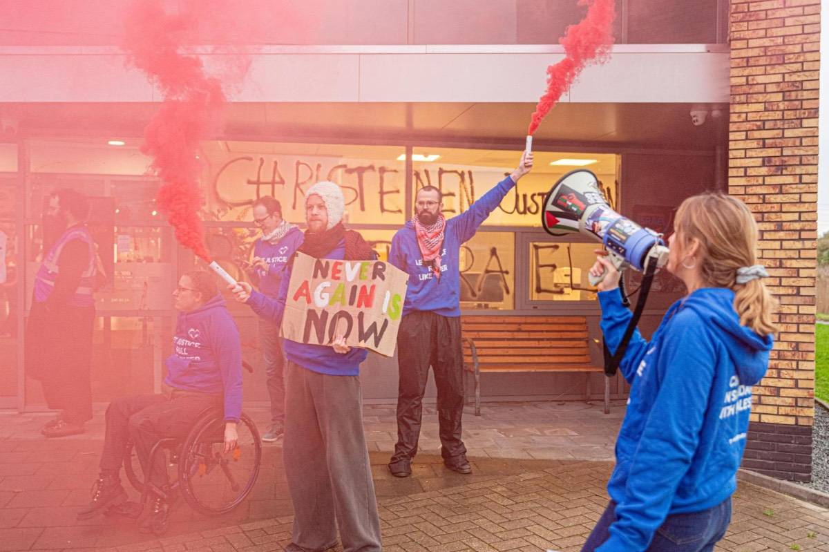 Activisten van Christelijk Collectief in blauwe t-shirts staan met brandende rode  rooktoortsen bij het distributiecentrum van Christenen voor Israel in Nijkerk